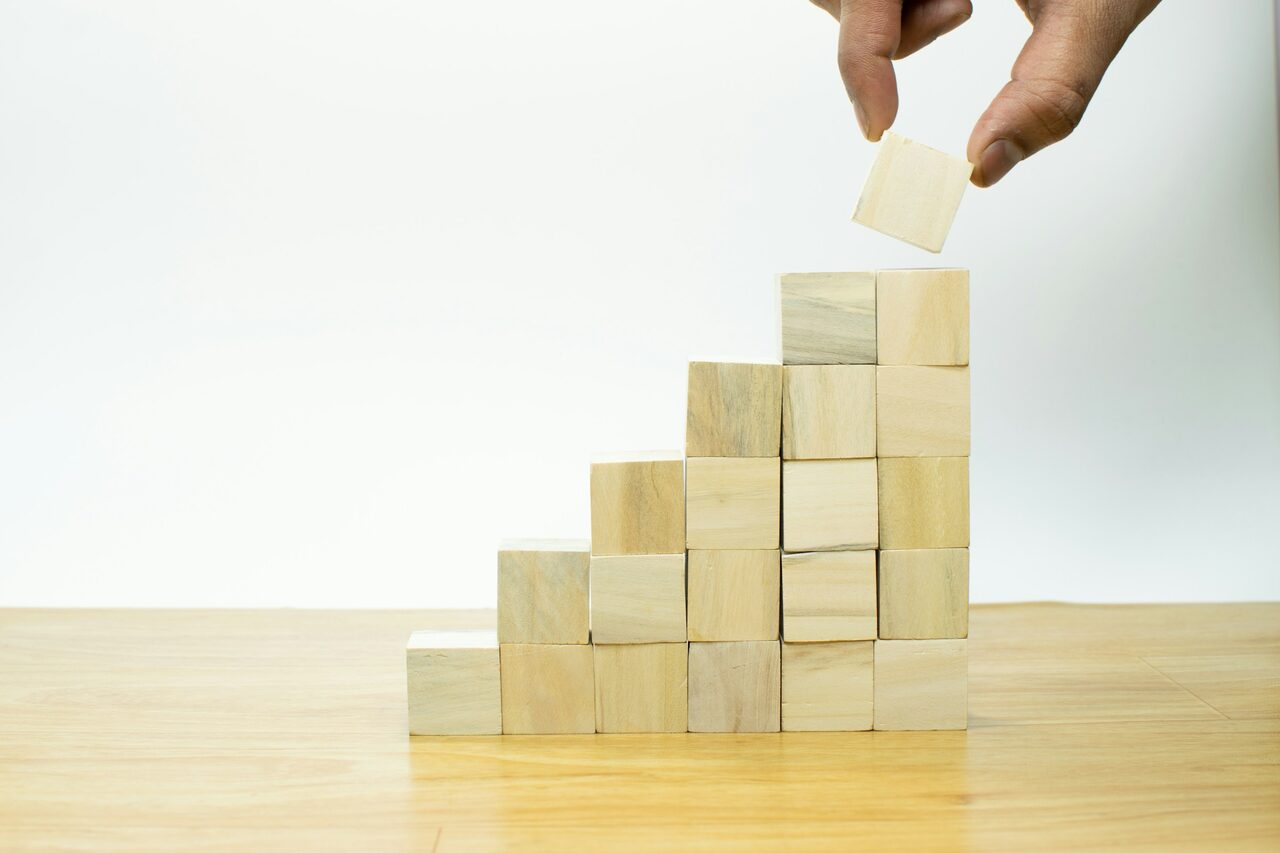 A hand placing a wooden block on a growing stack.
